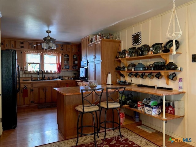 1101 S 17th St, Copperas Cove, TX 76522 - kitchen featuring black appliances, brown cabinetry, light wood-type flooring, a sink, and a kitchen bar
