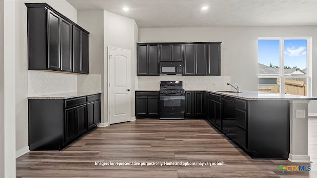 kitchen featuring kitchen peninsula, black appliances, sink, dark hardwood / wood-style floors, and light stone countertops