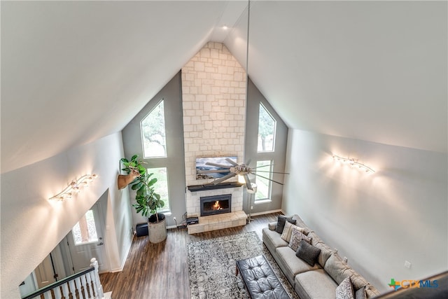 living room with a stone fireplace, dark hardwood / wood-style flooring, lofted ceiling, and ceiling fan