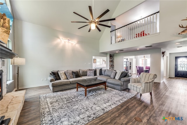 living room with a stone fireplace, high vaulted ceiling, dark wood-type flooring, and ceiling fan