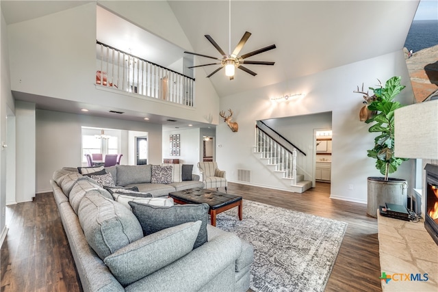 living room with high vaulted ceiling, a fireplace, dark wood-type flooring, and ceiling fan