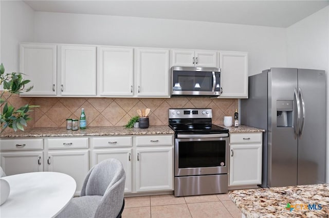 2105 Town Centre Dr Unit 42, Round Rock, TX 78664 - kitchen with appliances with stainless steel finishes, white cabinets, tasteful backsplash, light tile patterned flooring, and light stone counters
