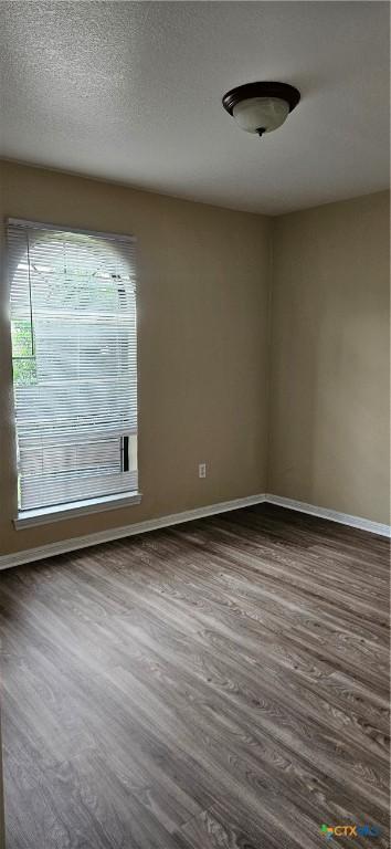 spare room with dark wood-style flooring and baseboards