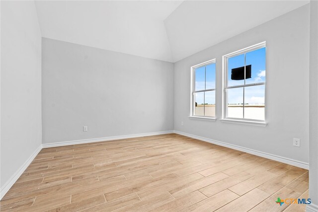 unfurnished room featuring vaulted ceiling and light hardwood / wood-style flooring