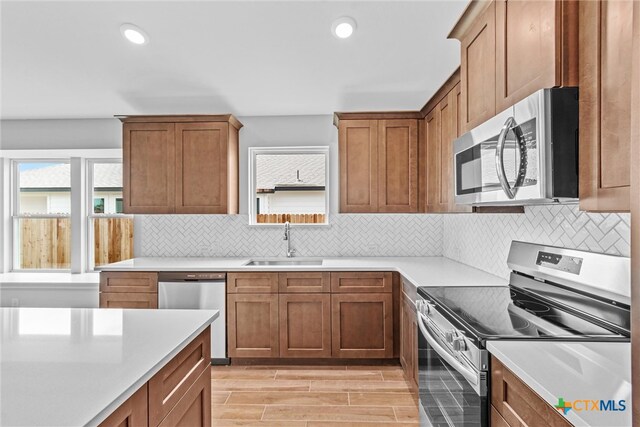 kitchen featuring light wood-type flooring, appliances with stainless steel finishes, sink, and backsplash