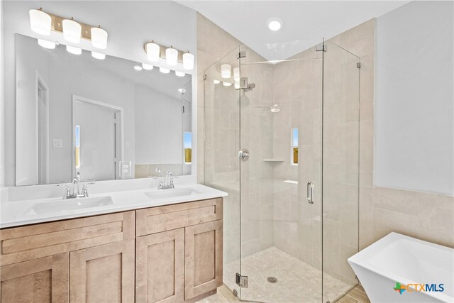 bathroom featuring independent shower and bath, vanity, and tile walls