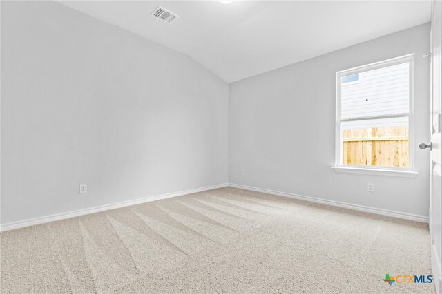 carpeted spare room with vaulted ceiling