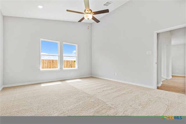 spare room featuring light wood-type flooring, ceiling fan, and high vaulted ceiling