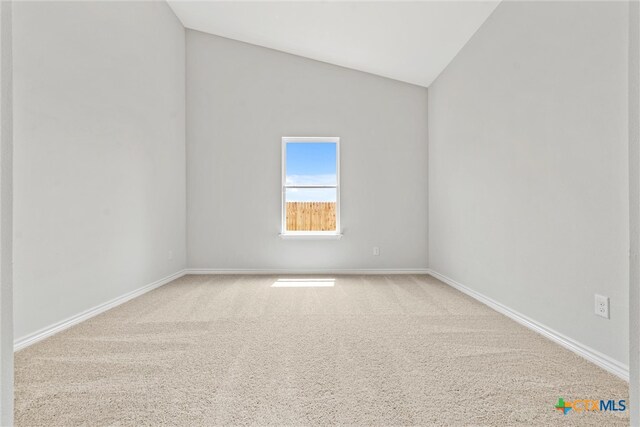 carpeted spare room with vaulted ceiling