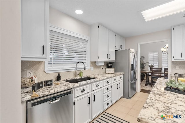 106 Westbrook Dr, Victoria, TX 77904 - kitchen with stainless steel appliances, decorative backsplash, white cabinets, light tile patterned floors, and light stone countertops