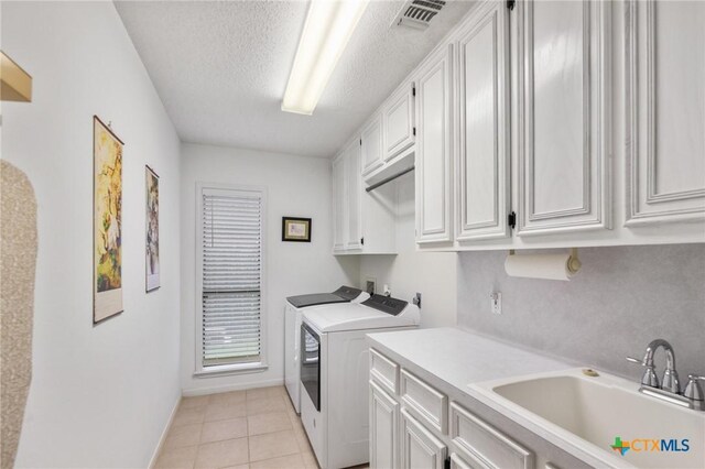 106 Westbrook Dr, Victoria, TX 77904 - washroom with cabinet space, washer and dryer, a textured ceiling, and light tile patterned floors