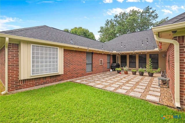 106 Westbrook Dr, Victoria, TX 77904 - rear view of house with brick siding, a patio, a shingled roof, and a yard