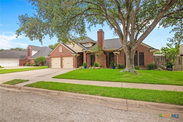 106 Westbrook Dr, Victoria, TX 77904 - traditional-style house with brick siding, a garage, concrete driveway, and a chimney