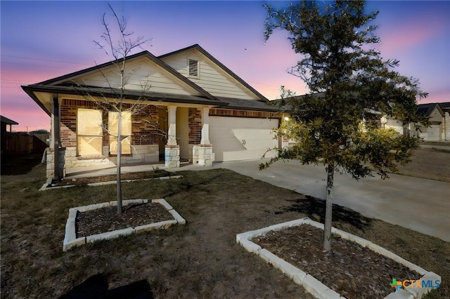 view of front of house with a porch, brick siding, a garage, and driveway