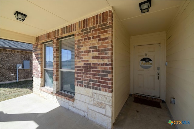 doorway to property featuring brick siding and a porch