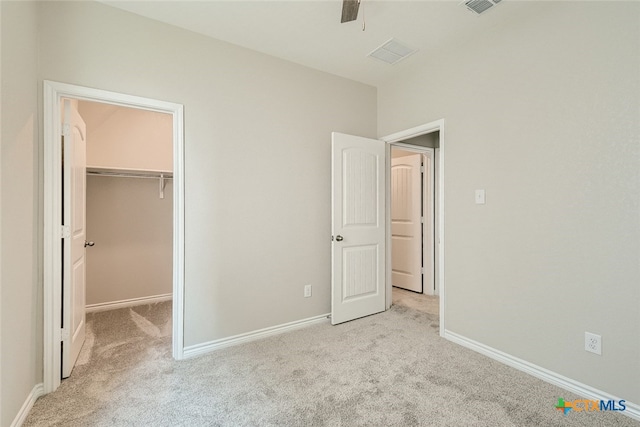 unfurnished bedroom featuring a spacious closet, a closet, ceiling fan, and light carpet