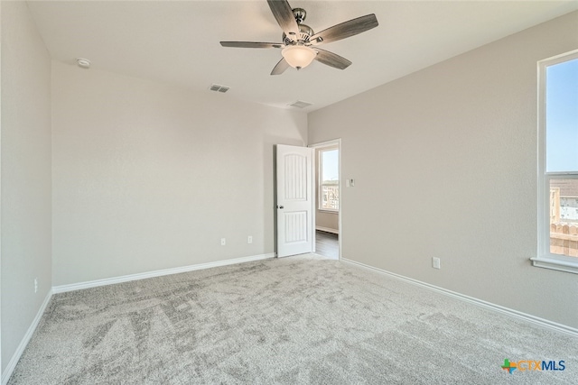 carpeted spare room with plenty of natural light and ceiling fan