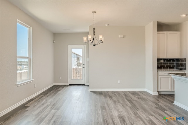 unfurnished dining area with a notable chandelier and light hardwood / wood-style flooring