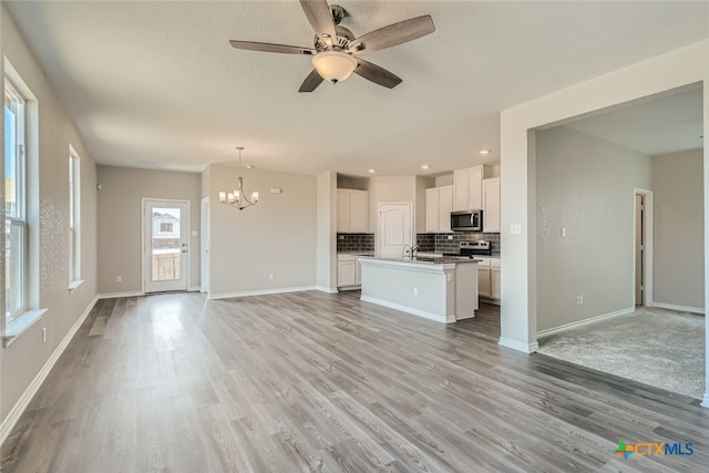 interior space featuring ceiling fan with notable chandelier and light hardwood / wood-style flooring