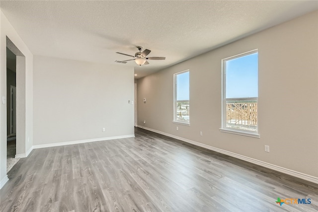 empty room featuring ceiling fan, light hardwood / wood-style flooring, and a textured ceiling