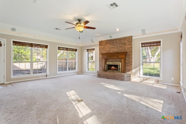 unfurnished living room with ceiling fan, a fireplace, light colored carpet, and a healthy amount of sunlight