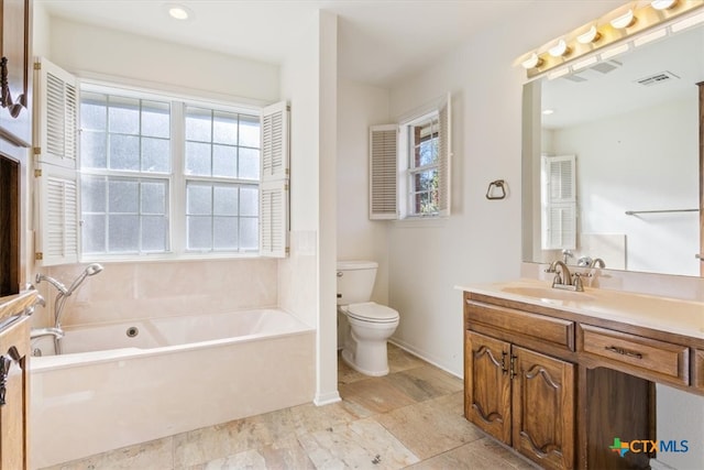 bathroom featuring vanity, a tub to relax in, and toilet