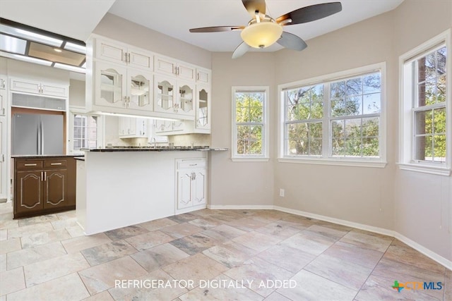 kitchen featuring kitchen peninsula, a wealth of natural light, white cabinets, and built in fridge