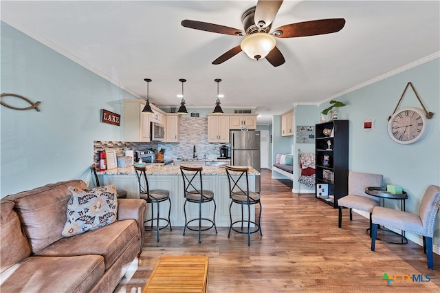 interior space with appliances with stainless steel finishes, pendant lighting, light hardwood / wood-style floors, kitchen peninsula, and cream cabinetry