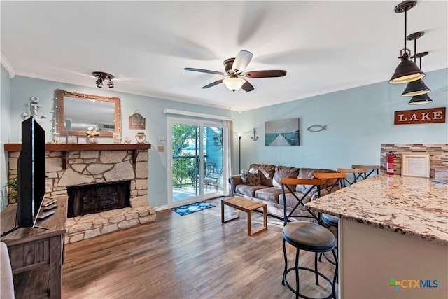 living room featuring ceiling fan, hardwood / wood-style flooring, ornamental molding, and a fireplace