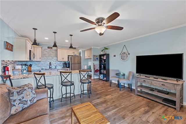 living room with ceiling fan, sink, light wood-type flooring, and crown molding