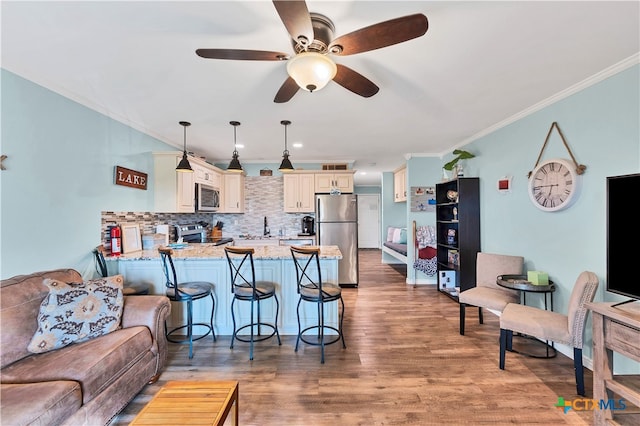 kitchen featuring stainless steel appliances, kitchen peninsula, light stone counters, wood-type flooring, and pendant lighting