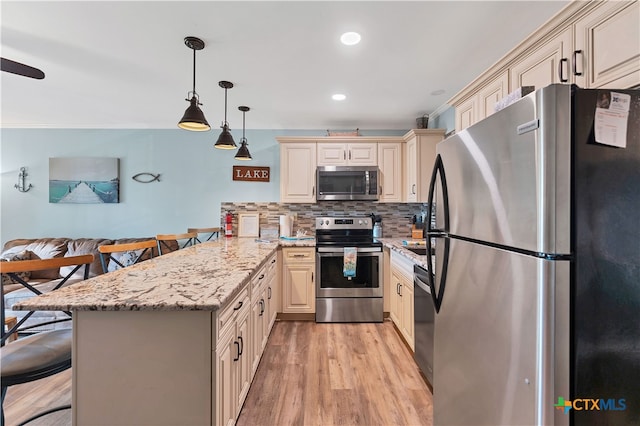 kitchen featuring light stone counters, kitchen peninsula, a breakfast bar, appliances with stainless steel finishes, and decorative light fixtures