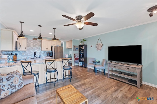 living room featuring light hardwood / wood-style floors, ceiling fan, sink, and crown molding