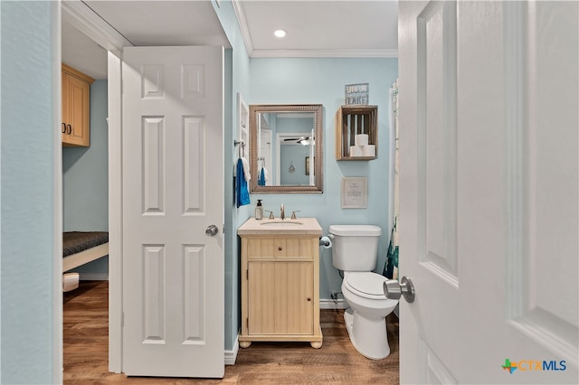 bathroom featuring toilet, vanity, wood-type flooring, and ornamental molding