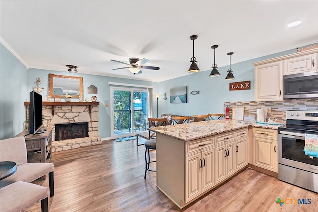 kitchen featuring a kitchen bar, light hardwood / wood-style floors, kitchen peninsula, hanging light fixtures, and appliances with stainless steel finishes