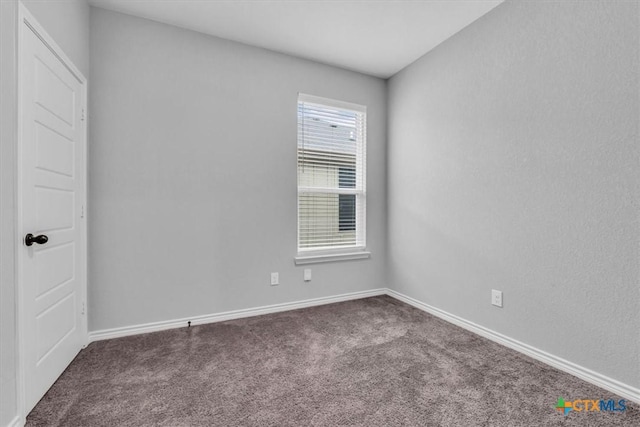 unfurnished room with dark colored carpet and baseboards