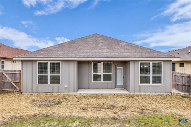 back of house with a yard, board and batten siding, a patio area, and fence