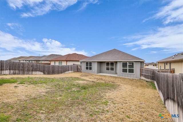 rear view of property with a fenced backyard and a lawn