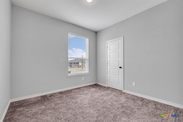 carpeted empty room featuring baseboards