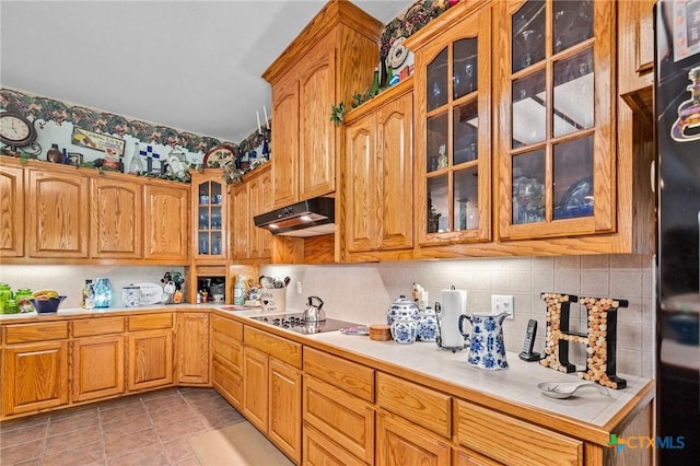 kitchen with decorative backsplash, light countertops, under cabinet range hood, and black electric cooktop