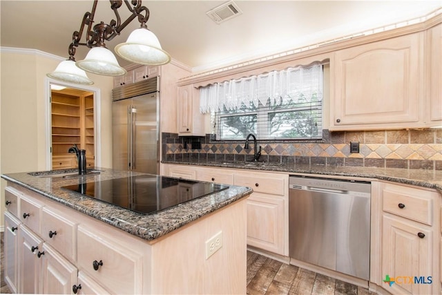 kitchen featuring an island with sink, stainless steel appliances, a sink, and hanging light fixtures