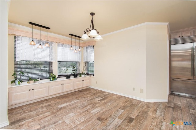 unfurnished dining area featuring light wood finished floors, baseboards, a chandelier, and crown molding