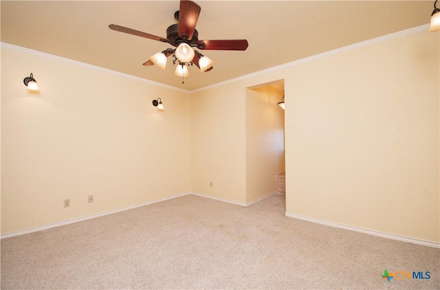 spare room featuring ornamental molding, light carpet, baseboards, and a ceiling fan