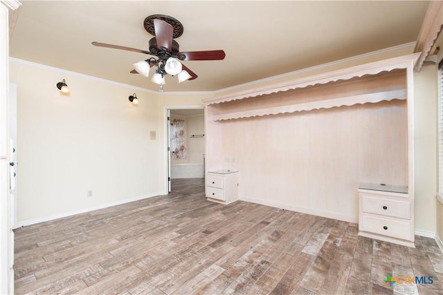 empty room with ornamental molding, wood finished floors, and baseboards