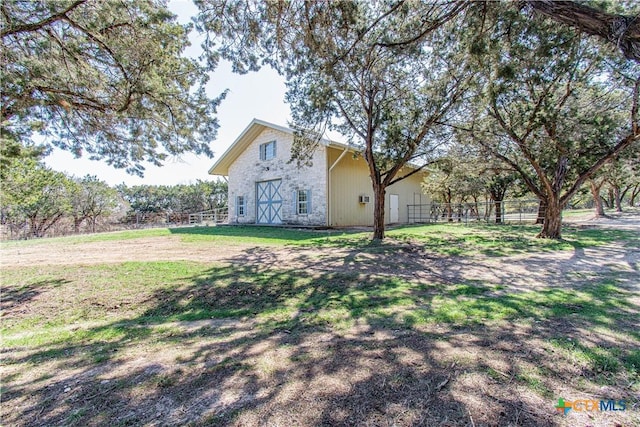 view of yard featuring a barn and fence