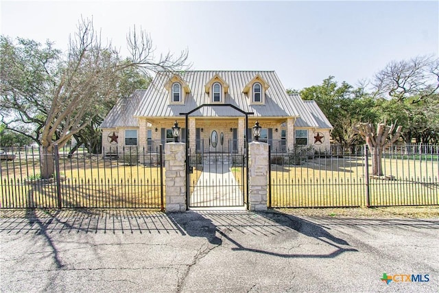 view of front of home with metal roof, stone siding, a fenced front yard, and a gate