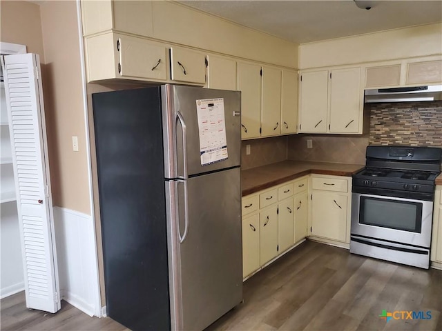 kitchen with backsplash, appliances with stainless steel finishes, dark hardwood / wood-style flooring, and cream cabinets