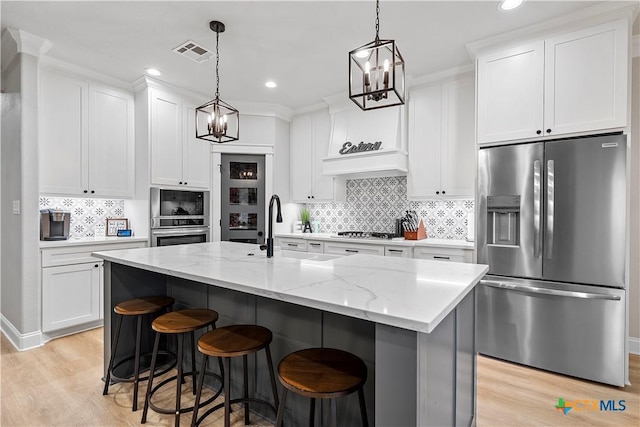 kitchen with white cabinets, stainless steel appliances, and a center island with sink