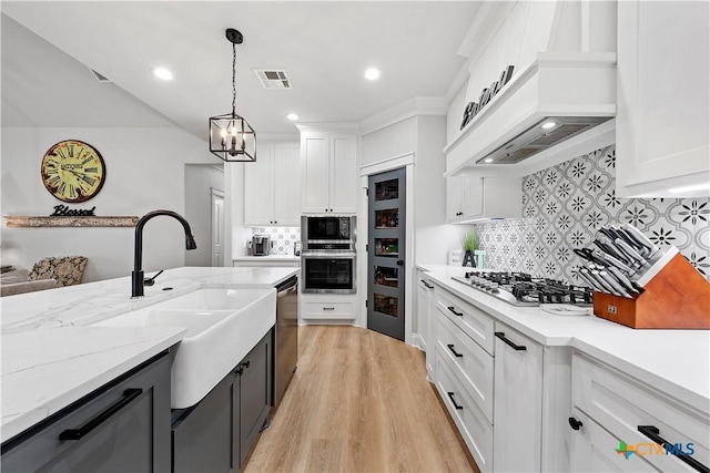 kitchen featuring premium range hood, pendant lighting, stainless steel appliances, light wood-type flooring, and white cabinets