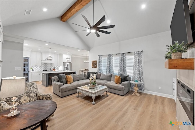 living room with sink, beamed ceiling, ceiling fan, light hardwood / wood-style flooring, and high vaulted ceiling